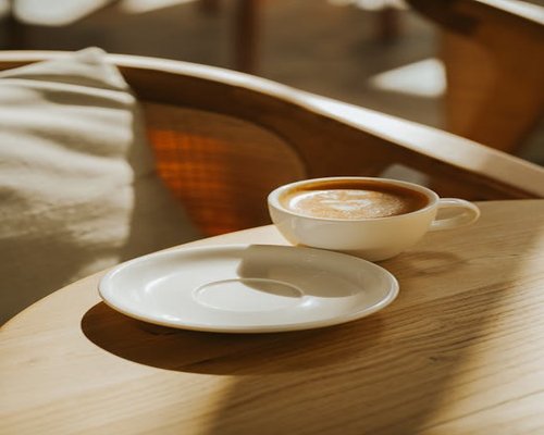 A warm cup of coffee on a wooden table with soft morning light